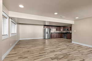 Kitchen featuring dark countertops, open floor plan, stainless steel appliances, light wood-type flooring, and recessed lighting