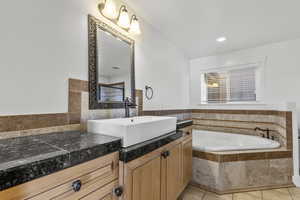 Bathroom with vanity, a bath, light tile patterned floors, and recessed lighting