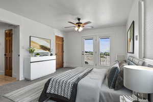 Staged primary bedroom featuring light colored carpet, access to exterior, ceiling fan, and light tile patterned floors