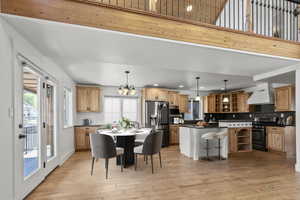Staged dining room and kitchen featuring light wood-type flooring, recessed lighting, and a chandelier