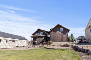 View of front facade with a front yard, board and batten siding, and stairway