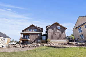 Back of house with a yard and a balcony
