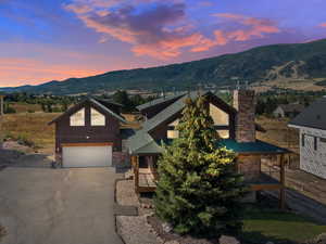 View of front of house featuring a chimney, driveway, a garage, and a mountain view