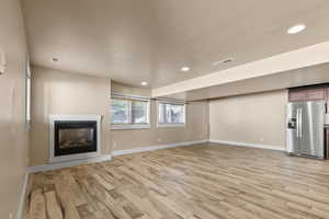 Unfurnished living room with a glass covered fireplace, light wood-style floors, and recessed lighting