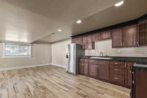 Kitchen with a textured ceiling, glass insert cabinets, gas stove, stainless steel refrigerator with ice dispenser, and recessed lighting