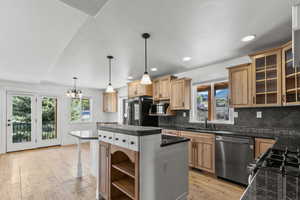 Kitchen with backsplash, decorative light fixtures, appliances, light wood-style flooring, and recessed lighting
