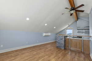 ADU above the garage - kitchen featuring wood finished floors, a ceiling fan, brown cabinets, a wall unit AC, and recessed lighting