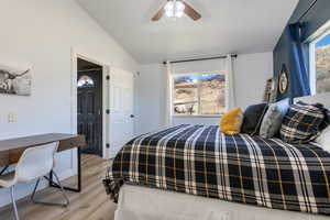 Bedroom featuring light wood-type flooring, lofted ceiling, a ceiling fan, and an office area