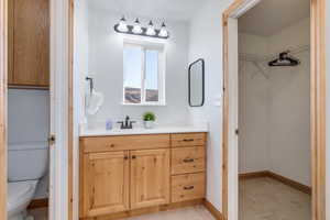 Bathroom with a walk in closet, vanity, and light tile patterned flooring