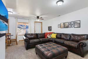 Carpeted living room featuring a ceiling fan and baseboards