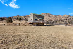 Rear view of house featuring a deck with mountain view, a lawn, and stucco siding
