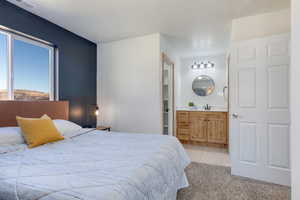 Bedroom featuring light carpet, light tile patterned floors, connected bathroom, and a mountain view