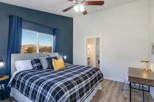 Bedroom with wood finished floors, ceiling fan, a mountain view, and connected bathroom