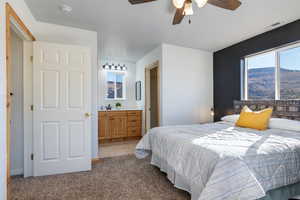 Bedroom with light carpet, ceiling fan, ensuite bathroom, and light tile patterned floors