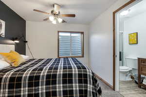 Bedroom featuring ceiling fan, light carpet, and ensuite bathroom