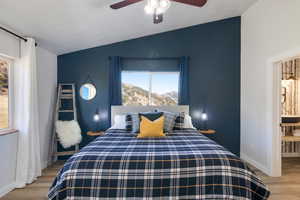 Bedroom featuring light wood finished floors, a mountain view, vaulted ceiling, and ceiling fan