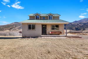 View of front of house featuring a mountain view, a porch, a front lawn, and stucco siding