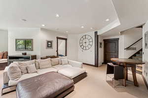 Living area featuring stairs, recessed lighting, and light colored carpet