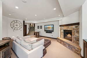 Living area featuring recessed lighting, a fireplace, light colored carpet, and stairway