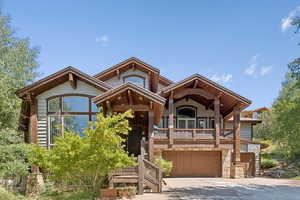 View of front facade with concrete driveway, an attached garage, stone siding, and covered porch