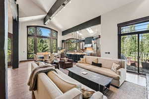 Living room with beamed ceiling, high vaulted ceiling, wood-type flooring, and a skylight