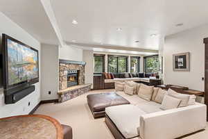 Living room featuring light colored carpet, a stone fireplace, and recessed lighting