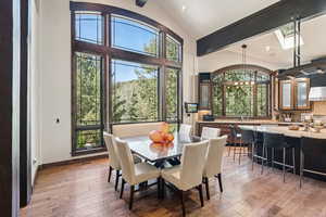 Dining space with a chandelier, light wood finished floors, healthy amount of natural light, and a skylight