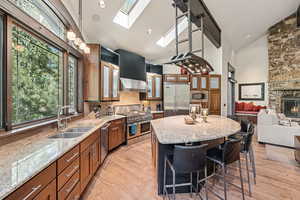 Kitchen featuring a center island, light wood finished floors, a skylight, brown cabinets, and a kitchen breakfast bar