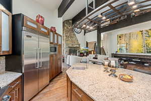 Kitchen with brown cabinets, open floor plan, light stone countertops, and built in appliances