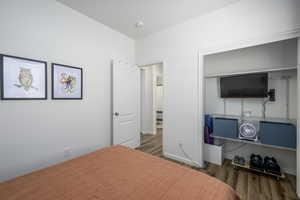 Bedroom with dark wood-style flooring and a closet
