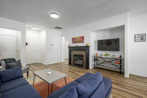 Living room with light wood-type flooring and a tiled fireplace