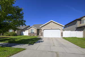 Ranch-style home featuring brick siding, concrete driveway, a garage, stucco siding, and a residential view