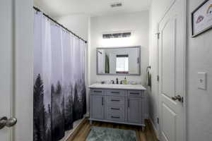 Bathroom with dark wood-style floors, vanity, and a shower with shower curtain