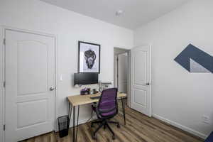 Home office with dark wood-type flooring and baseboards