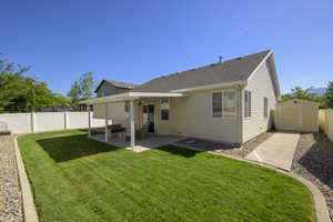 Back of property featuring a storage shed, a fenced backyard, a patio, and roof with shingles