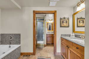 Full bathroom featuring two vanities, light tile patterned floors, a bath, and a stall shower