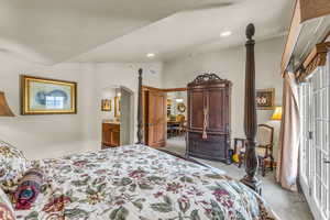 Carpeted bedroom with arched walkways, connected bathroom, and recessed lighting