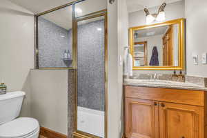 Full bathroom featuring a stall shower, vanity, and a textured wall