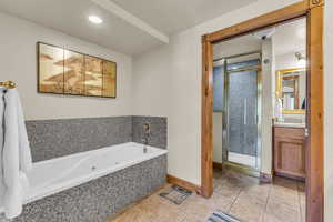 Full bath featuring vanity, a stall shower, light tile patterned flooring, a whirlpool tub, and recessed lighting