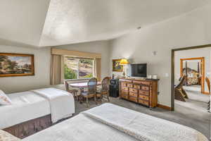 Carpeted bedroom featuring vaulted ceiling and a textured ceiling