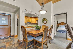 Dining room with high vaulted ceiling, arched walkways, wood ceiling, and dark stone finish flooring