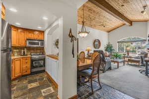 Kitchen with stone tile flooring, tasteful backsplash, wood ceiling, appliances with stainless steel finishes, and light countertops