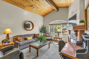 Carpeted living room with a wooden ceiling with exposed beams, high vaulted ceiling, and a desk