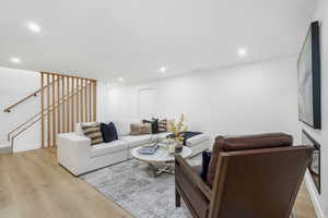 Living area featuring light wood-type flooring, recessed lighting, and stairway