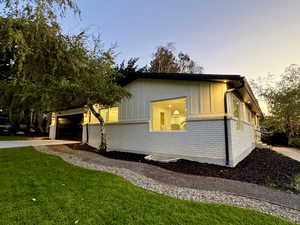 View of home's exterior with brick siding, board and batten siding, driveway, a lawn, and an attached garage