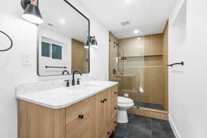 Bathroom with vanity, a stall shower, dark tile patterned floors, and recessed lighting
