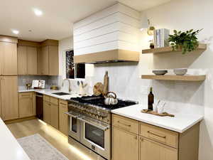 Kitchen with light brown cabinetry, range with two ovens, open shelves, and recessed lighting