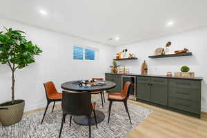 Dining room featuring light wood-style flooring, wine cooler, a bar, and recessed lighting