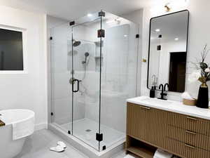 Bathroom featuring a shower stall, a freestanding bath, vanity, and tile patterned flooring