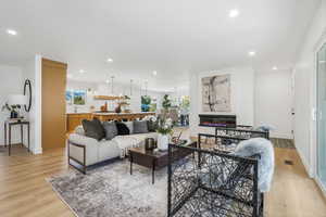 Living area featuring recessed lighting, light wood-type flooring, and a glass covered fireplace